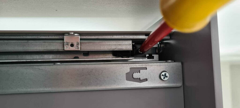 Re-inserting drawer rail spring clip screw.