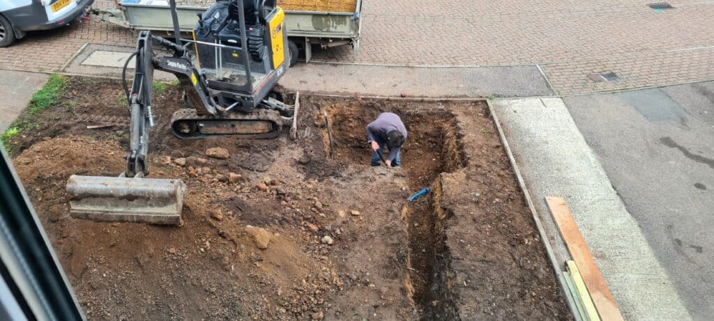 Carefully checking the depth of the soak away pit to avoid hitting services