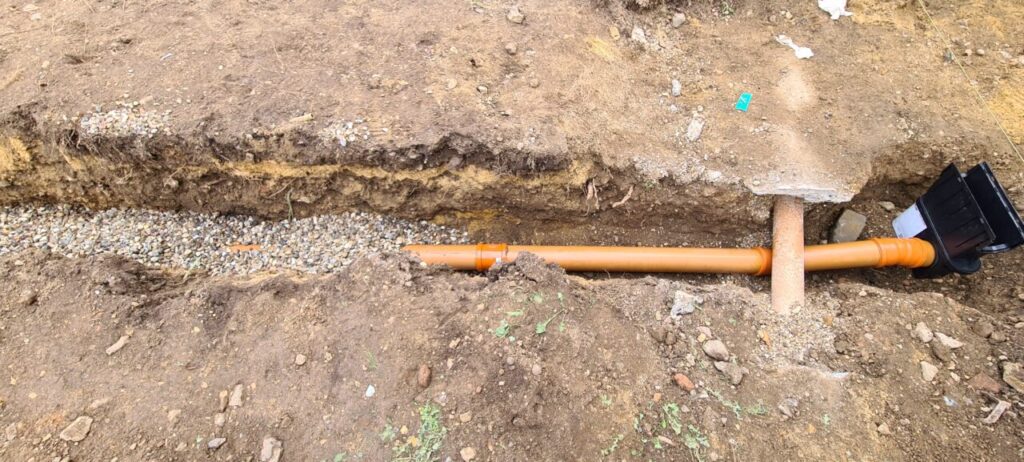 Drainage pipe from sump to soakaway pit being covered in pea shingle