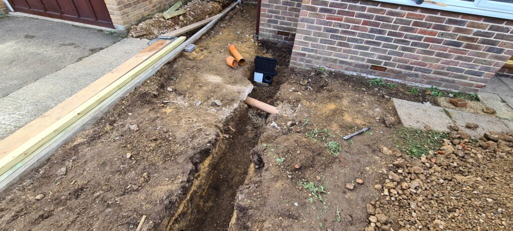 Trench from soak away to channel drain sump for drainage pipe